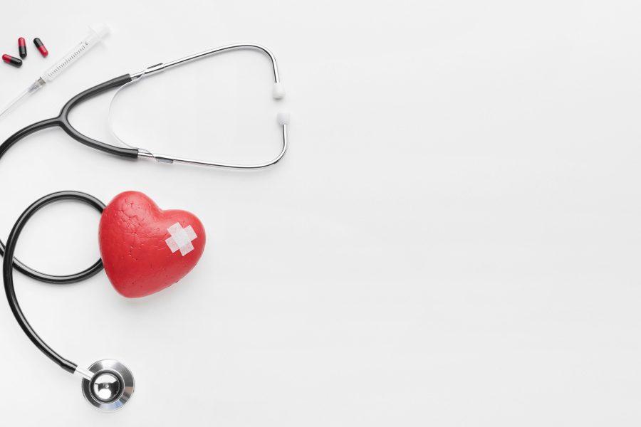 syringe, capsules and stethoscope with red stitched heart